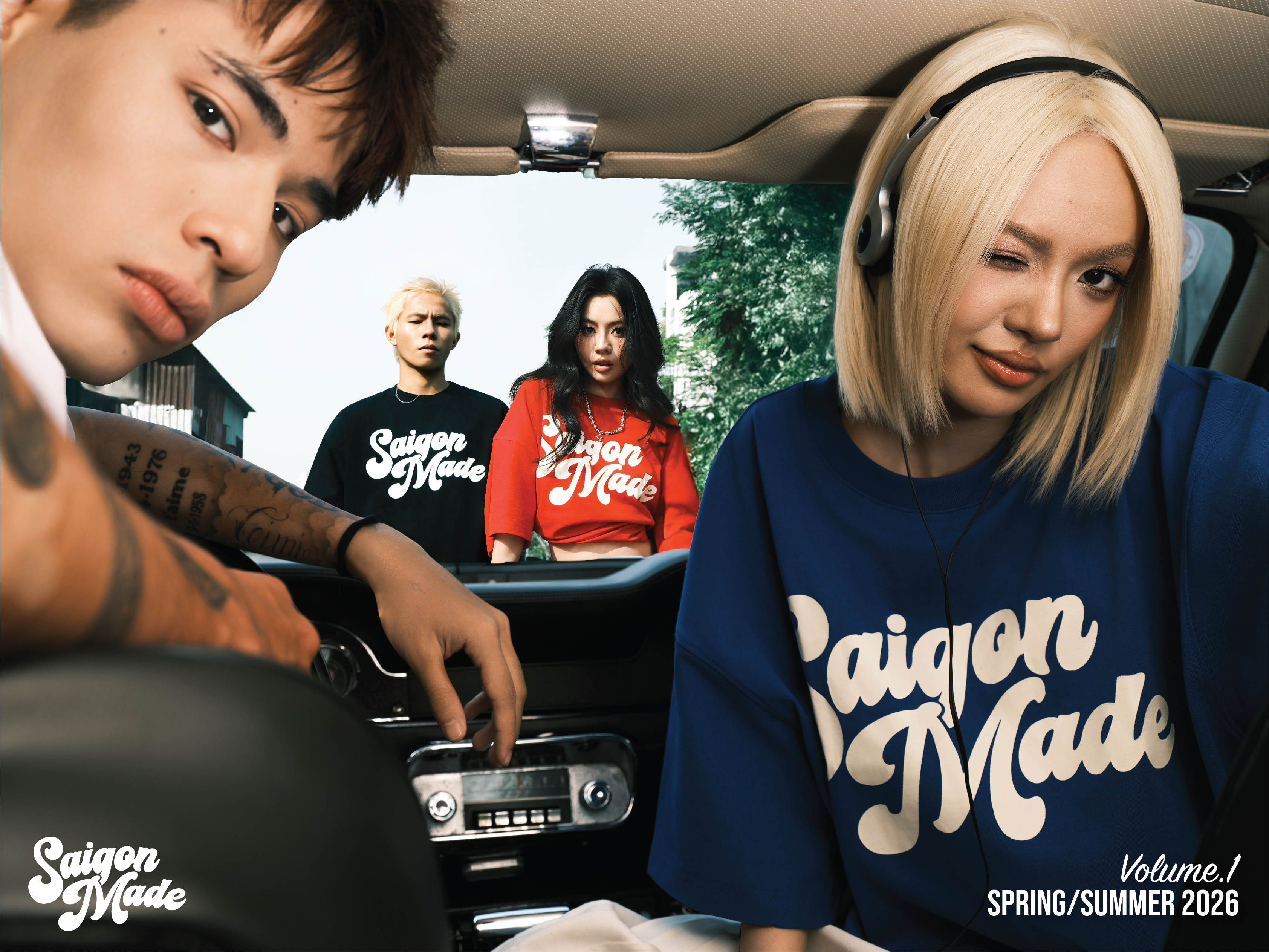 Two people sitting inside a car with 'Saigon Made' branding, featuring a collage of four people wearing similar shirts.